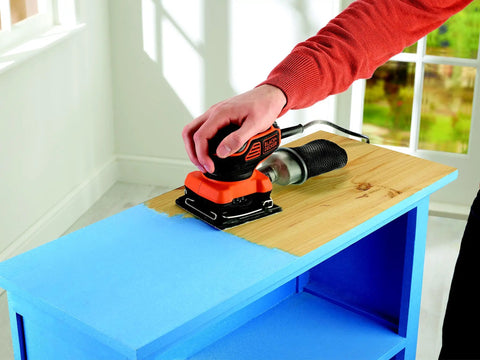 Person using a Quarter Sheet Orbital Palm Sander Professional Grade 220 Watt Motor Featuring A Snappy Pressure Trigger Switch Lightweight Orange Body for sanding wood.