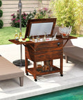 Wooden Patio Cooler Cart With 54 Quart Capacity Rolling Beverage Bar On Wheels With Bottle Opener Drain Plug And Locking Wheels Perfect For Poolside Backyards Parties And BBQs, shown by a pool with open lid.