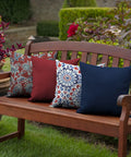 Outdoor bench with assorted patterned toss pillows, including a sapphire blue, showcasing all-weather and fade-resistant fabric.
