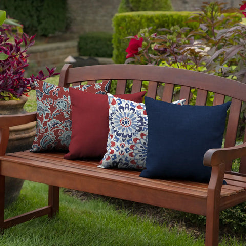 Outdoor bench with assorted patterned toss pillows, including a sapphire blue, showcasing all-weather and fade-resistant fabric.