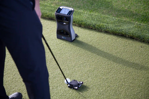 Golfer using GCQuad Golf Launch Monitor With Quadrascopic Four Camera System For Precise Ball And Club Head Data on grass.