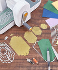 Five set of thirty six bookmark die cuts and tag dies with embossing stencils for scrapbooking, displayed next to a cutting machine.