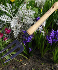 Mid Size Garden Fork For Loosening And Aerating Soil With Hardened Boron Steel Tines And Ash Hardwood Handle in flower bed