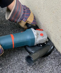 Universal 5 Inch Angle Grinder Slurp Guard Dust Shroud With Quick Clamp Fitting and Shop Vac Hose Adapter for 39 to 51mm Grinders in use on surface.
