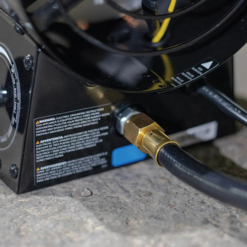 Close-up of 125,000 BTU Forced Air Propane Space Heater connections with 10 ft hose and regulator on concrete surface.