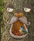 Tree Face Bird Feeder Outdoor Decor With Glow In The Dark Eyes Old Man Tree Hugger Sculpture Dope Yard Art Garden Ornament For Birds And Birdwatchers Perfect For Gardens And Lawns installed on a tree with a bird in the seed dispenser.