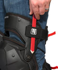 Person wearing Weight Dispersion Foam Pro Grade Knee Pads With Thigh Stabilization For Floor And Roof Projects Built Tough Poly Shell And 1680D Lining Adjustable Fit For All Day Comfort One Pair while holding a pencil against the strap.
