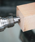 Woodturning lathe center MT2 (live/drive) close-up on a light wood block; metal, threaded shank.
