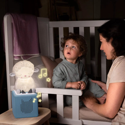 Night Light For Kids Sleep Aid With Sleepy Sheep Audio Play Character emitting glow on bedside in child's room with parent.