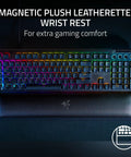 Top Tier Mechanical Gaming Keyboard With Kickass Clicky Green Switches And Lightning Fast Actuation Paired With Sleek Per Key RGB Underglow Lighting, featuring a magnetic plush leatherette wrist rest for comfort.