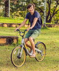 Person riding a bike with 24-inch wheels through a grassy park setting on a sunny day.