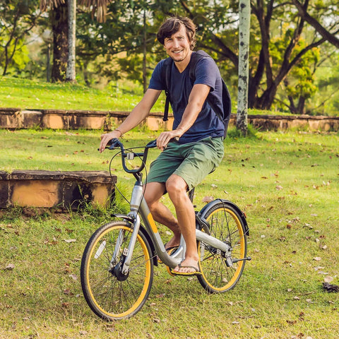 Person riding a bike with 24-inch wheels through a grassy park setting on a sunny day.