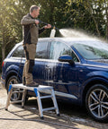 Person washing car using Height Adjustable Work Platform And Folding Aluminum Step Ladder Portable And Lightweight Yet Built Tough With 330 Lb Rating Perfect For Vehicle Washes Window Cleaning Do It Yourself Projects And Maintenance