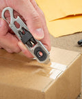 Hand using DoohicKey Ratchet Key Tool Keychain Friendly Pocket Multitool With Carabiner Clip on cardboard box