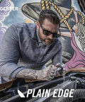 Man using Jukebox EDC Folding Pocket Knife With Straight Edge Flipper Blade for car maintenance with mural background.