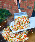 Extra Large Stainless Steel Griddle Food Mover Spatula With 5 Cup Capacity For Rice Vegetables And More Built For Grills And Cookouts Perfect BBQ Tool For Turning Flipping And Transferring A Big Batch Of Food being used to transfer stir-fried rice and vegetables from grill to plate.