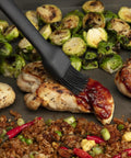 Grilled chicken and vegetables with basting brush on top, part of the 24 Piece Griddle Tool Set With Storage Tote Stainless Steel Flat Top Grill Accessories Spatulas Smash Burger Press Melting Dome Tongs Scraper Egg Rings Bottle Sprayers Salt And Pepper Shakers Cookout Ready For BBQ Tailgates And Camping.