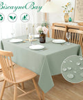 54x54 Inch Sage Square Tablecloth, Linen Like, Water Resistant And Washable, Ideal For Kitchen Dining, Picnics, Patio And Outdoor Parties, Restaurant Tables, Fits 24x24 To 42x42 Inch Square Tables, shown on a dining table with chairs and dishware