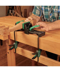 Rock Solid 6 Inch Quick Action Bench Vise With 300 Pound Clamping Power in use clamping wood on a workbench.