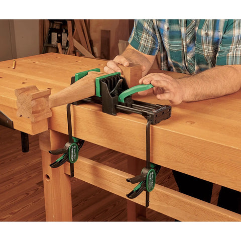 Rock Solid 6 Inch Quick Action Bench Vise With 300 Pound Clamping Power in use clamping wood on a workbench.