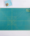 24 By 36 Inch Self Healing Rotary Cutting Mat Double Sided With Grids For Quilting Sewing Fabric Crafts on a craft table