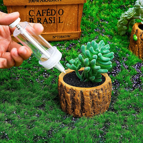 Hand using Mini Seed Dispenser And Hand Seeder Tool For Garden Planters with succulent in small pot on grassy surface.