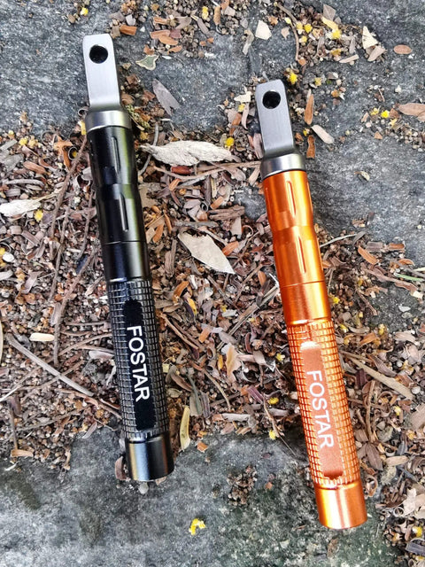 2 Pack Ferro Rod Fire Starter With Replaceable Flint in orange and black on ground, aluminum body, for camping hiking emergency.