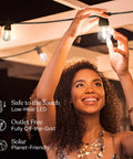 Woman enjoying the Solar Powered Outdoor String Lights 48 Ft Commercial Grade Waterproof Patio Lights With 15 Shatterproof LED Edison Bulbs Soft White