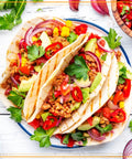 Colorful plate of tacos with fresh toppings including peppers, onions, and avocado, perfect for using with an Ultimate Taco Night Heated Lazy Susan Party Serving Set Shareable With Four Tortilla Holders And 20 Oz Fondue Pot For Burritos Nachos And Fajitas Perfect For Entertaining At Home Red.
