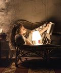 Cozy evening reading with Petit LED Lamp With Cordless Portable Power And Rechargeable Battery, white finish on nightstand.