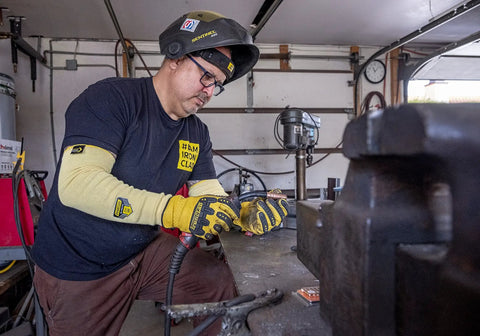 Man using a tool in a workshop wearing Heavy Duty Eighteen Inch Kevlar Arm Sleeves Featuring Legit A3 Cut Resistant Armor.