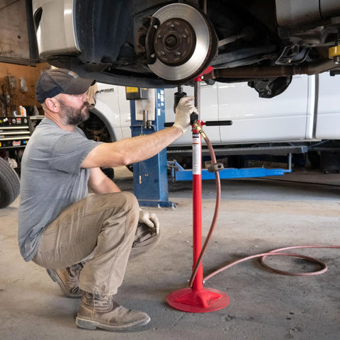 Short Underhoist Support Stand 1500 Lb Capacity Adjustable Height Range For Engine Swap And Suspension Work Fits Two Post Lifts Garage Wrenching Essential For Car Enthusiasts And Pro Mechanics in use by a mechanic.