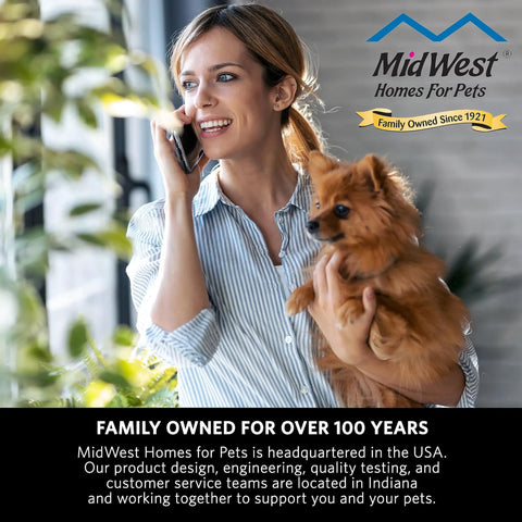 Woman holding dog in front of MidWest Homes for Pets sign, promoting family-owned pet safety gate business for over 100 years.