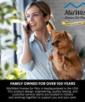 A woman holding a small dog in front of a banner for MidWest Homes for Pets, featuring information about family ownership.