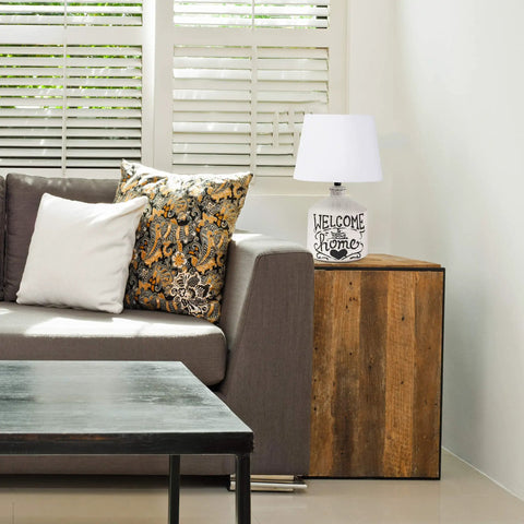 Welcome Home Rustic Ceramic Farmhouse Table Lamp With White Linen Shade on wood side table in modern living room.