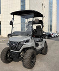 Two Seater Electric Golf Cart With Independent MacPherson Strut Suspension And Tuned Coil Spring Shocks parked outdoors.