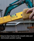 Heavy Duty Aluminum Torpedo Spirit Level With Bullseye Precision Vials Scratch Resistant Yellow Body And Built In Magnets For Dead On Marks And Knocked Out Layouts On Any Job Site Gig held in hand with construction background.
