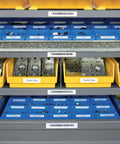 Blue and yellow storage bins on shelving labeled with barcodes and tags, organized for job site use.
