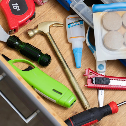 GreatNeck 5-in-1 hammer in a cluttered tool drawer with glue, tape measure, screwdrivers, and utility knives.