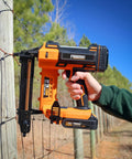 Hardcore 20V Cordless Fencing Stapler Kit Bundled With 16 Gauge 1 Inch Staples And Rock Solid 2AH Battery Plus Fast Charger And Roomy Tool Bag For Roughneck Builders in action on a fence post.