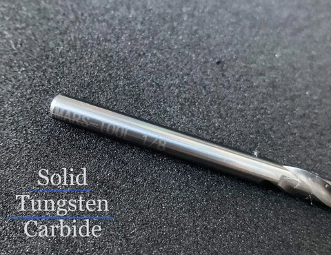 Close-up of a solid tungsten carbide drill bit showing text '1/8' on a textured background, for hardened steel metalwork.