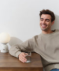 Person sitting beside 10 Inch Table Lamp With Marble Base And Frosted Glass Shade, Cozy Bedside Reading Light For Bedroom And Living Room.