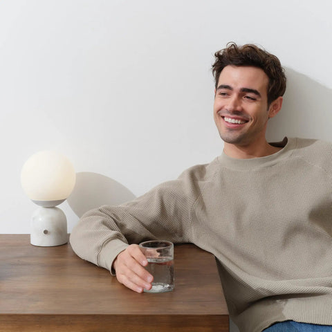 Person sitting beside 10 Inch Table Lamp With Marble Base And Frosted Glass Shade, Cozy Bedside Reading Light For Bedroom And Living Room.