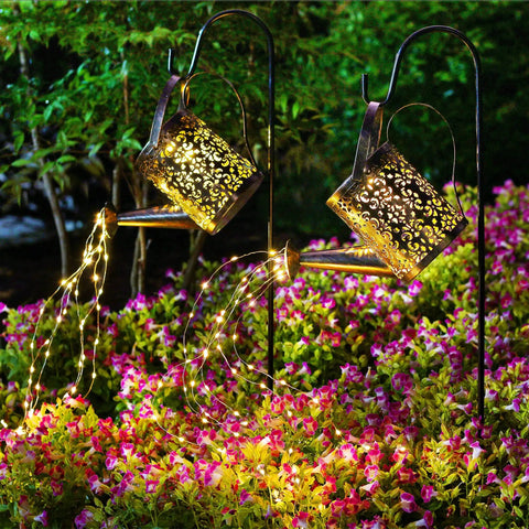 2 Pack Solar Waterfall Watering Can Lights For Garden illuminating flowers with LED copper strands at night.