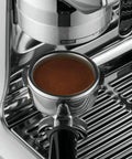 Heavy Duty Fully Automatic Espresso Machine With Slick Touchscreen Interface And Pro Grade Dual Boiler Rig For Killer Specialty Coffee At Home Featuring Precise Thermal Regulation And Smooth Simultaneous Brewing close-up of portafilter with ground coffee.