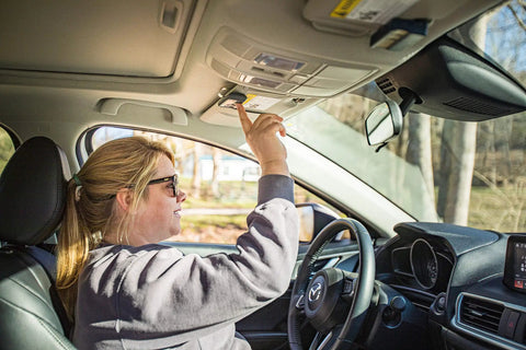 Person using 3 Button Gate Opener Remote Transmitter For Swing And Sliding Gates And Garage Doors in car, visor clip attached.