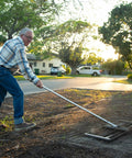 Man using Stainless Steel 30 Inch Lawn Level Rake Pro Grade Yard Tool For Even Grass And Smooth Soil Leveling in garden