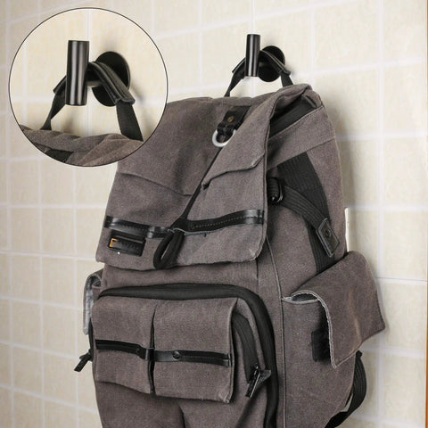 Three Pack Self Adhesive Stainless Steel Towel Hooks Black Matte Heavy Duty Wall Mounts holding a backpack on tile wall.