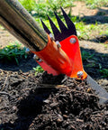 Close-up of 2 In 1 Garden Hoe And Weed Puller Rake with 60 Inch Adjustable Long Handle, digging soil in a garden.