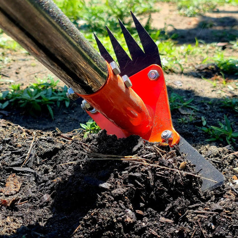 Close-up of 2 In 1 Garden Hoe And Weed Puller Rake with 60 Inch Adjustable Long Handle, digging soil in a garden.